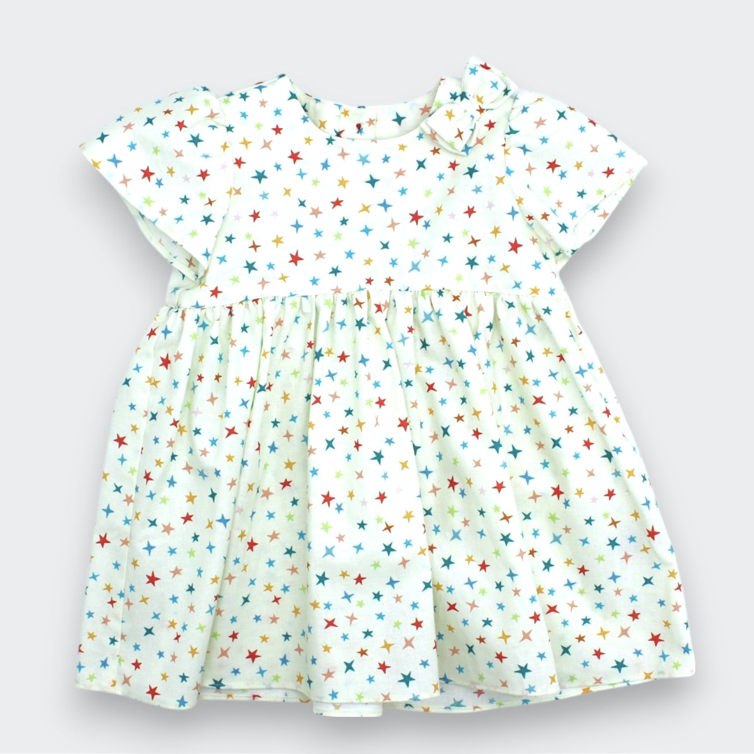 Children's dress with colorful star pattern on a light gray background