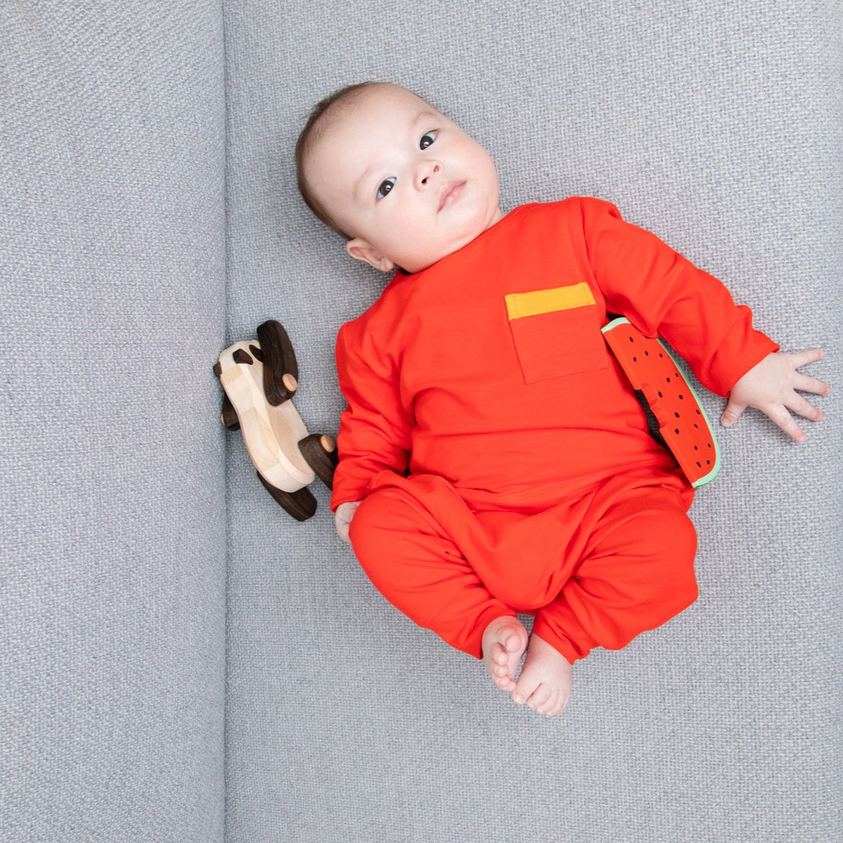Baby boy in vermillion red pants and long-sleeve shirt