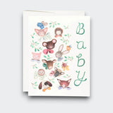 A white baby greeting card with “Baby” written vertically in green, surrounded by watercolor woodland animals including a rabbit, mouse, hedgehog, fox, and puppy. A white envelope sits behind it.