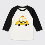 A children's raglan long-sleeve shirt with black sleeves and a white body, featuring a graphic of a yellow NYC taxi on the front.