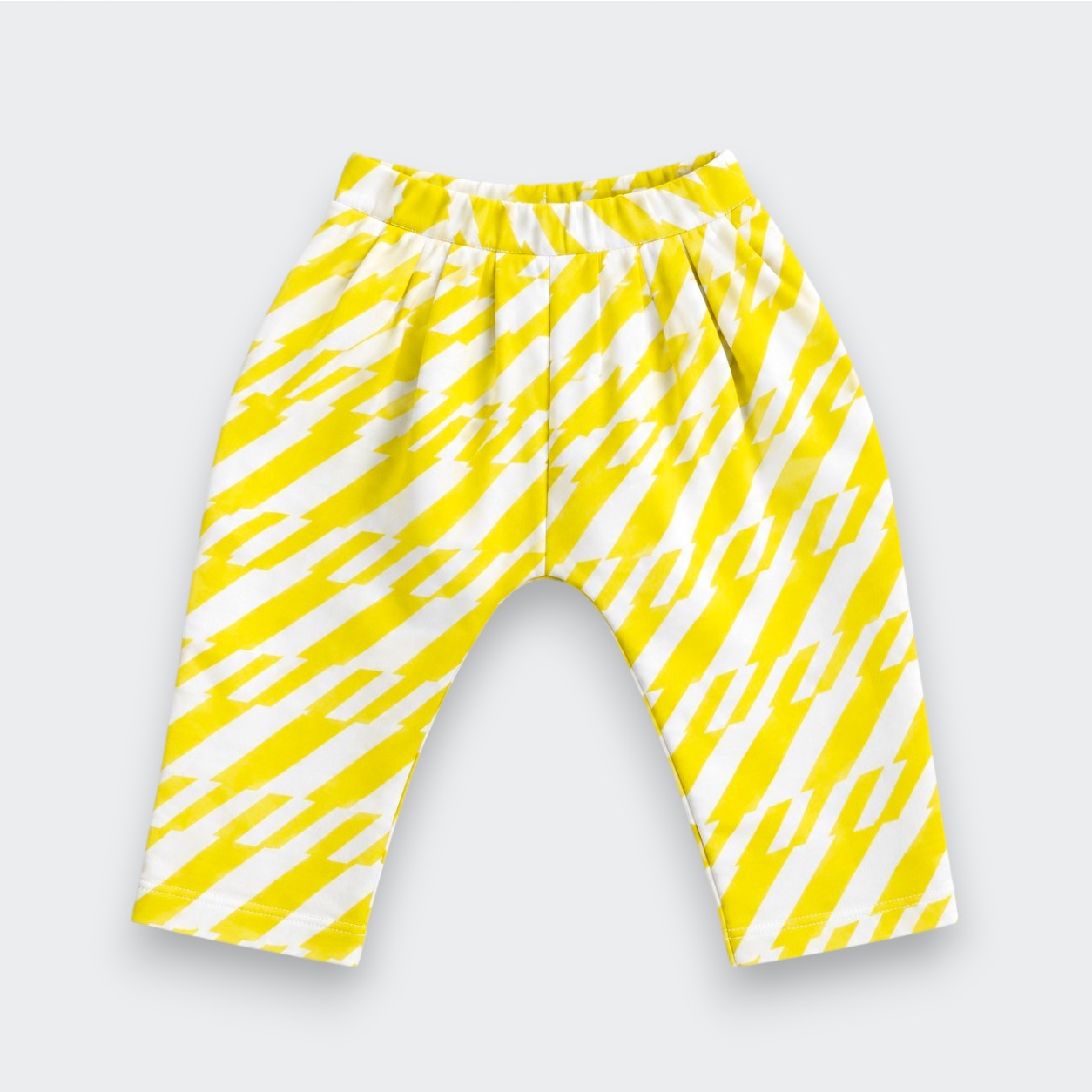 A pair of Little Moony children's pants featuring a bold yellow and white diagonal zigzag pattern, displayed flat against a light gray background.