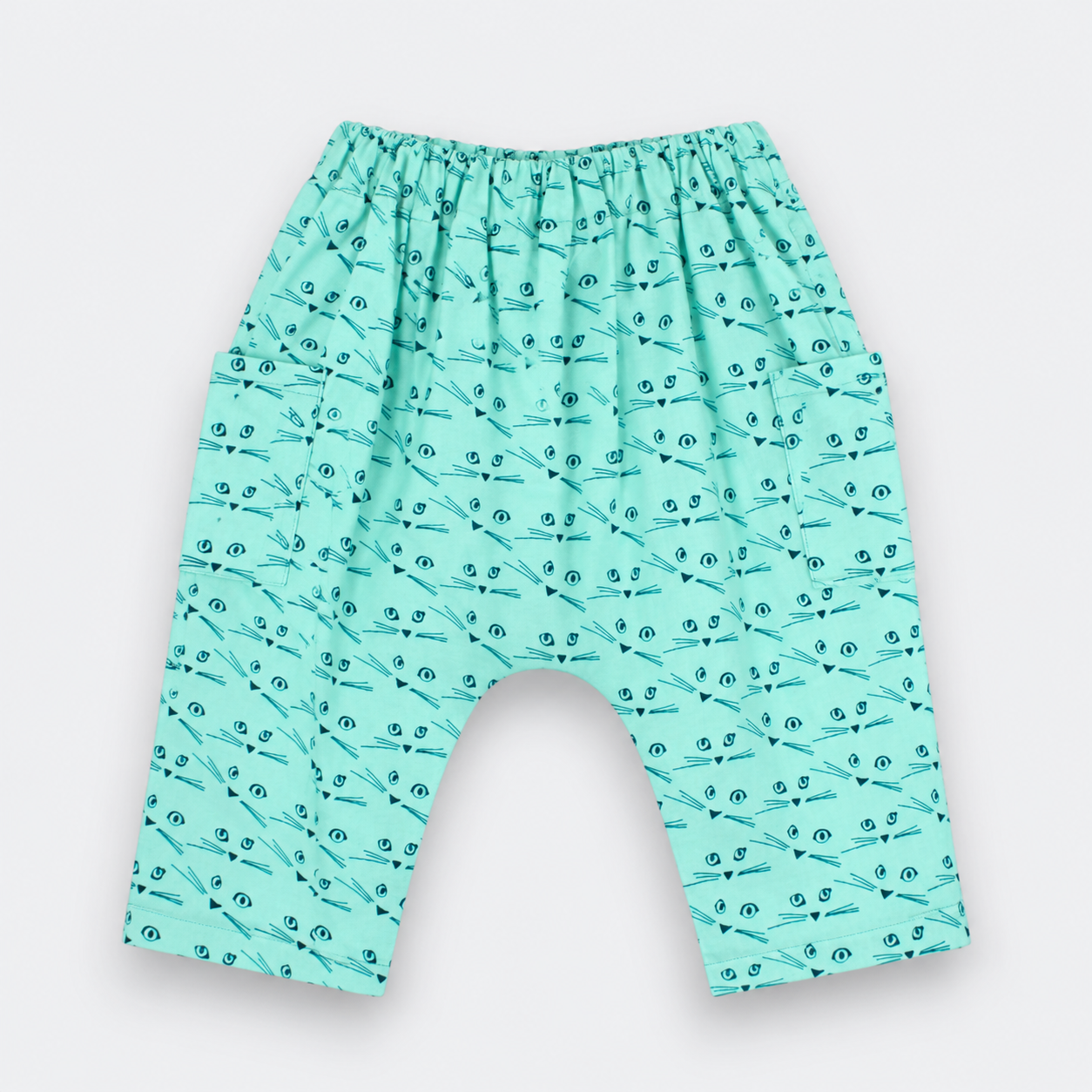 A pair of baby pants in mint green with a repeating black dragonfly pattern, featuring an elastic waistband and a wide leg design.