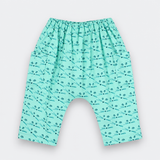 A pair of baby pants in mint green with a repeating black dragonfly pattern, featuring an elastic waistband and a wide leg design.