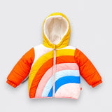 A children’s hooded puffer jacket laid flat on a light gray background. It has a yellow hood with white plush lining, orange quilted sleeves, a pale pink front zipper, and curved rainbow panels in yellow, orange, pink, light blue, and bright blue.