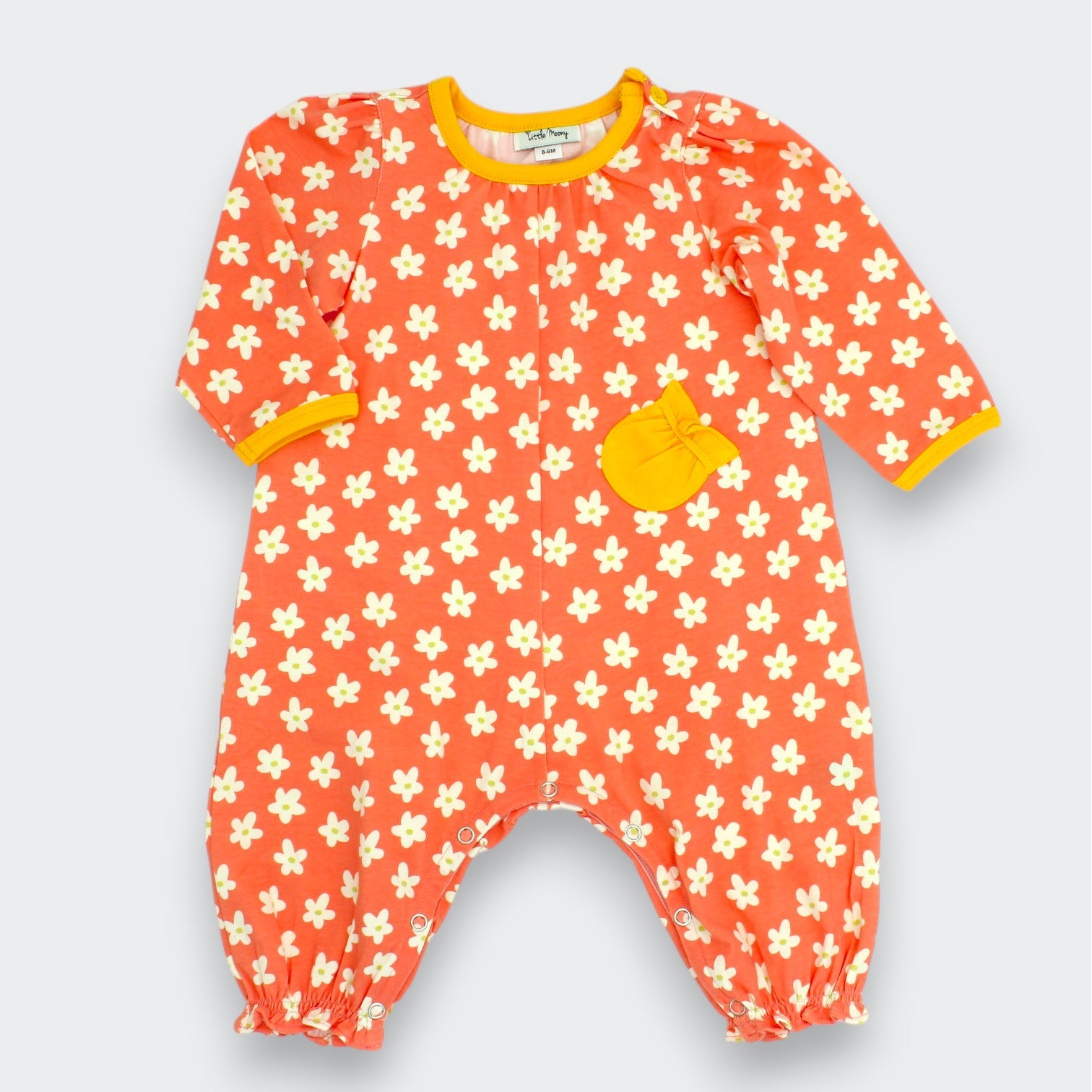 Little Moony Daisy floral baby romper in coral with cream daisy print, marigold ribbed trim at collar and cuffs, and ruffled chest pocket, full body view on white background
