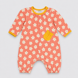 A baby long-sleeve romper in a coral pink color, featuring a white daisy floral pattern, a yellow pocket, and yellow trim on the collar and cuffs, laid flat on a light gray background.