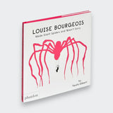 An angled view of Louise Bourgeois Made Giant Spiders and Wasn’t Sorry, showing its pink spine and white cover with a large bright pink spider and a tiny figure swinging beneath it.