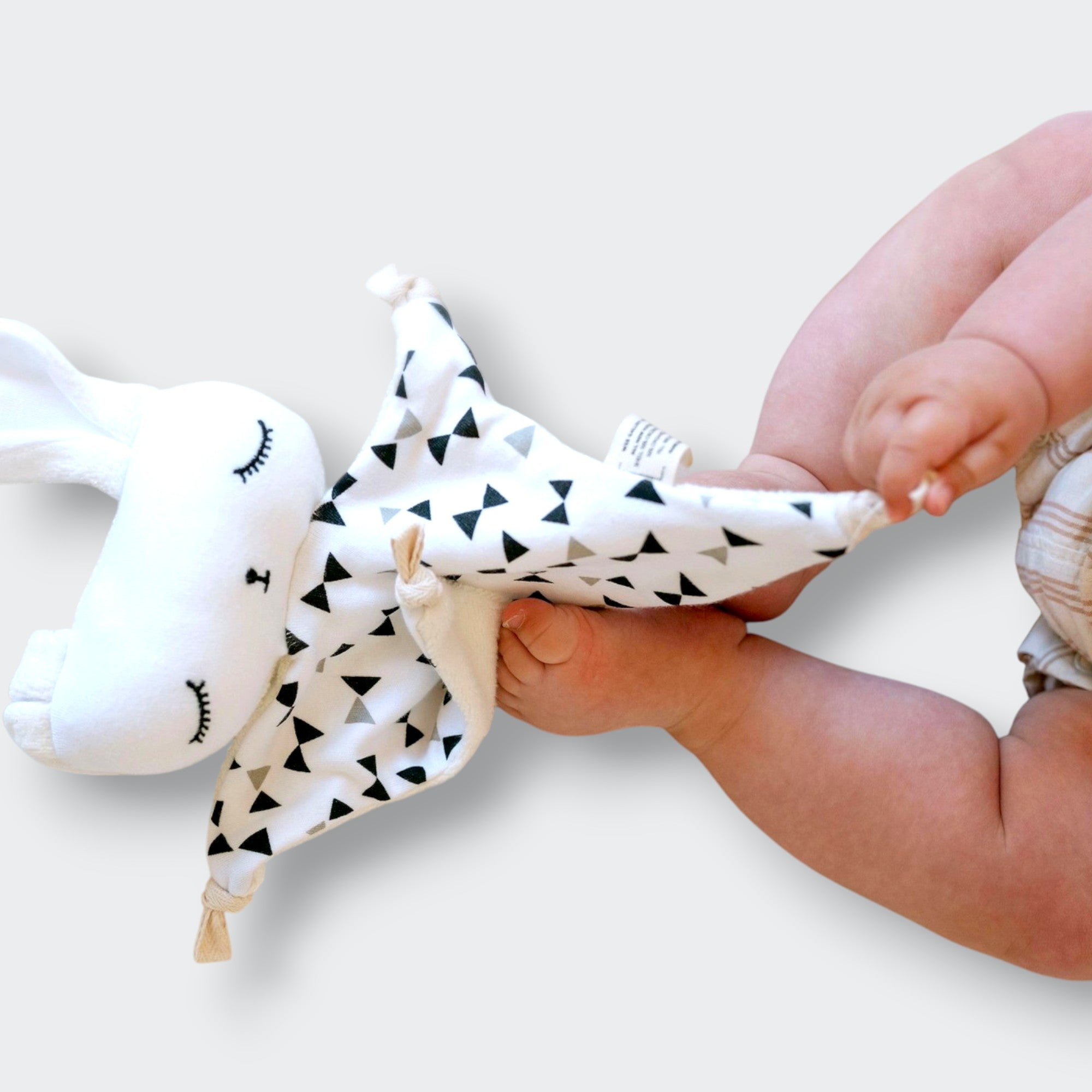 Little Moony Organic Cuddle Bunny Lovey with a soft, snuggly design and sweet bow tie detail for babies and toddlers played by a baby.