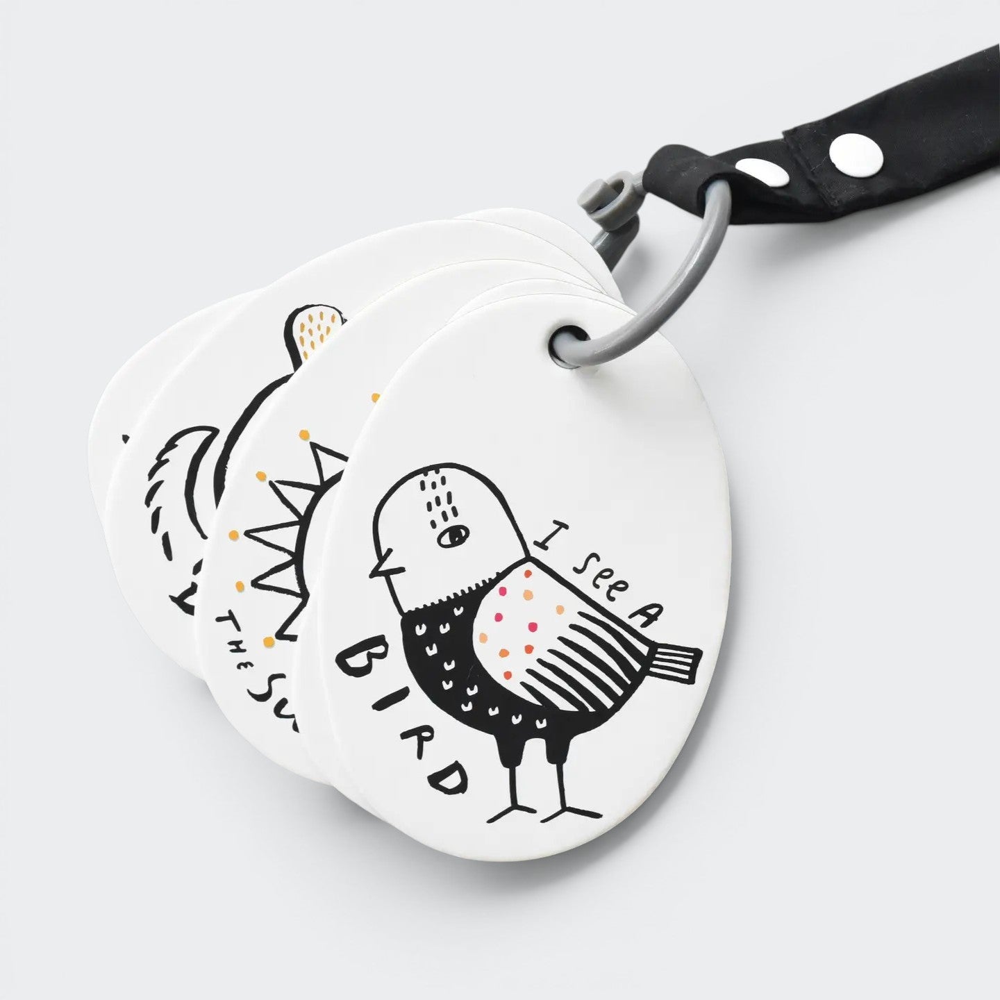 Round white tag with black and white illustrations of a bird and text, attached to a black strap. Baby stroller cards.