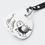 Round white tag with black and white illustrations of a bird and text, attached to a black strap. Baby stroller cards.