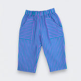 A pair of children's pants featuring a vibrant teal and purple striped pattern, laid flat against a light gray background.