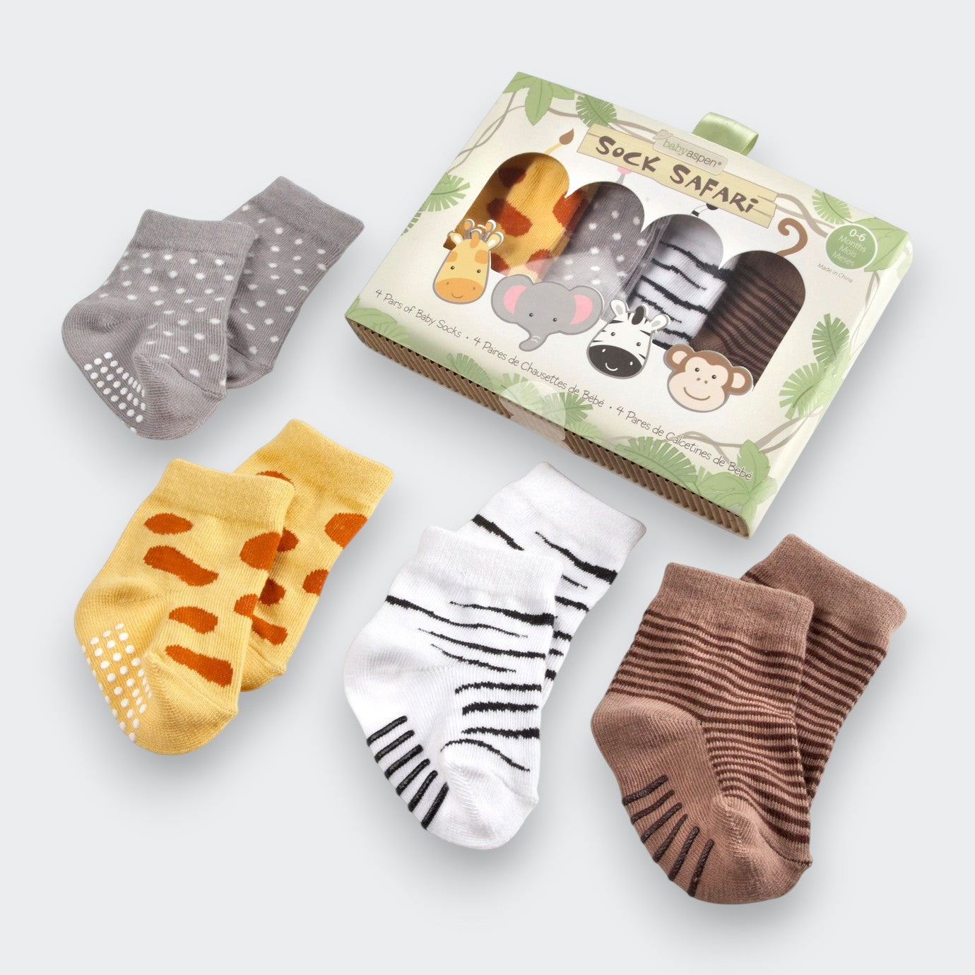 Four pairs of safari-themed baby socks displayed beside their “Sock Safari” gift box on a light gray background. The socks are gray with white spots, yellow with brown giraffe-like patches, white with black zebra stripes, and brown with narrow stripes.