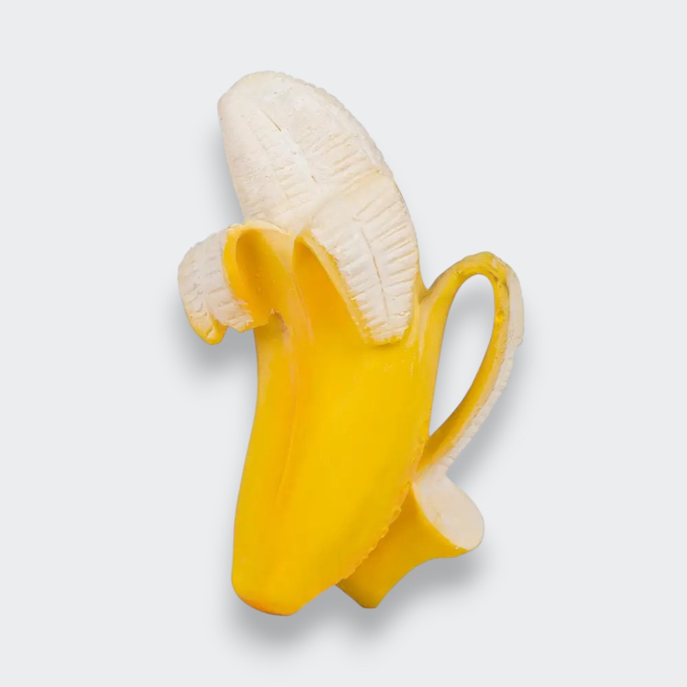 A banana-shaped baby teether on a light gray background. It has a textured cream-colored banana, a bright yellow peel folded back around it, and a loop handle on one side.