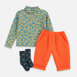 A children's three-piece outfit set featuring a long-sleeve mock neck shirt with a blue and yellow floral pattern, bright orange pants with white polka dots, and navy blue socks with a small red and green pattern, all laid flat on a white background.