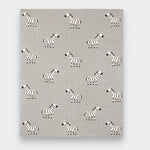 A gray knit baby blanket spread flat on a light gray background, showing an allover pattern of small black-and-white zebras arranged in rows.