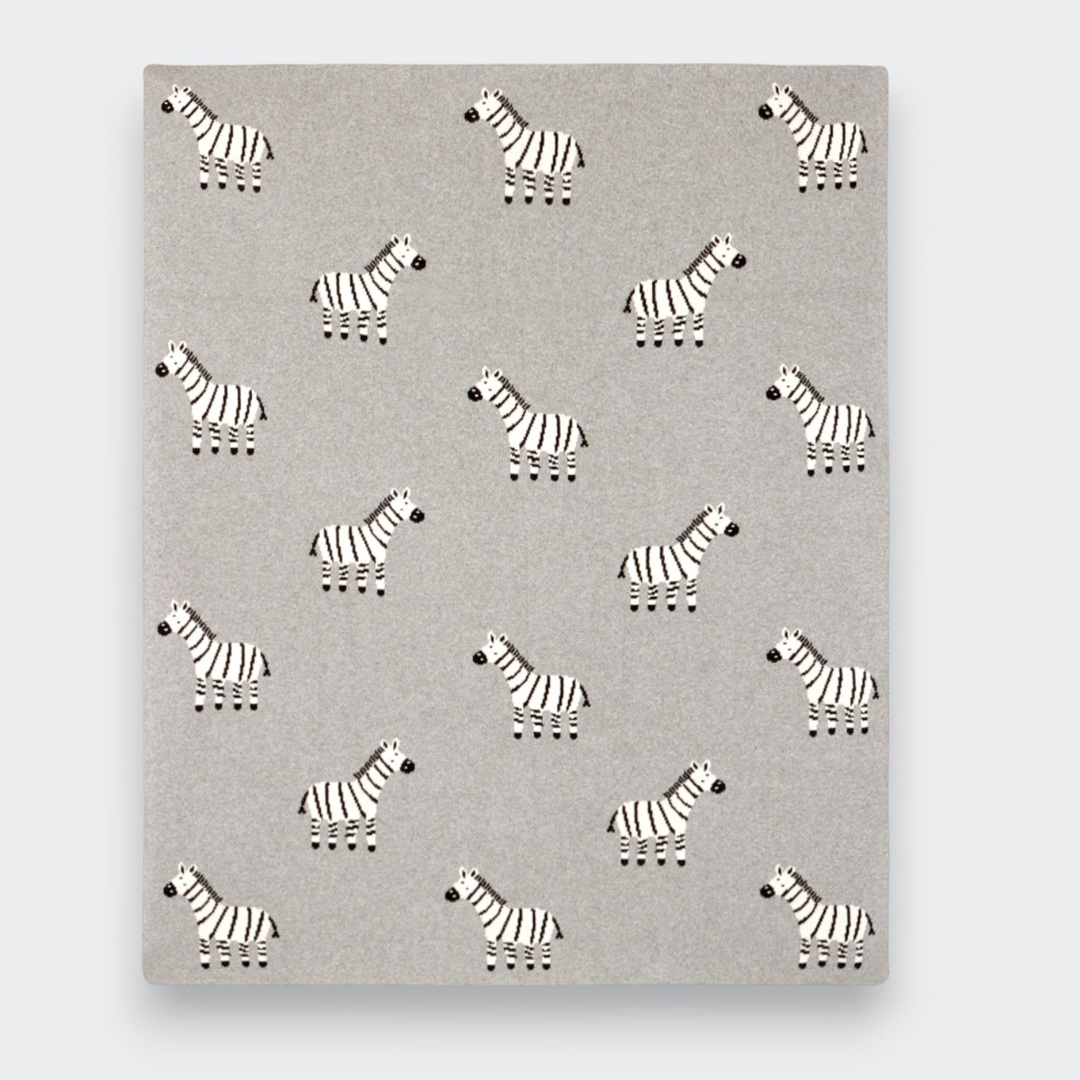 A gray knit baby blanket spread flat on a light gray background, showing an allover pattern of small black-and-white zebras arranged in rows.