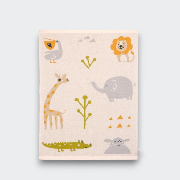 A folded cream baby blanket on a light gray background, printed with colorful jungle animals including a toucan, lion, giraffe, elephant, crocodile, and hippo, alongside small trees and geometric shapes.