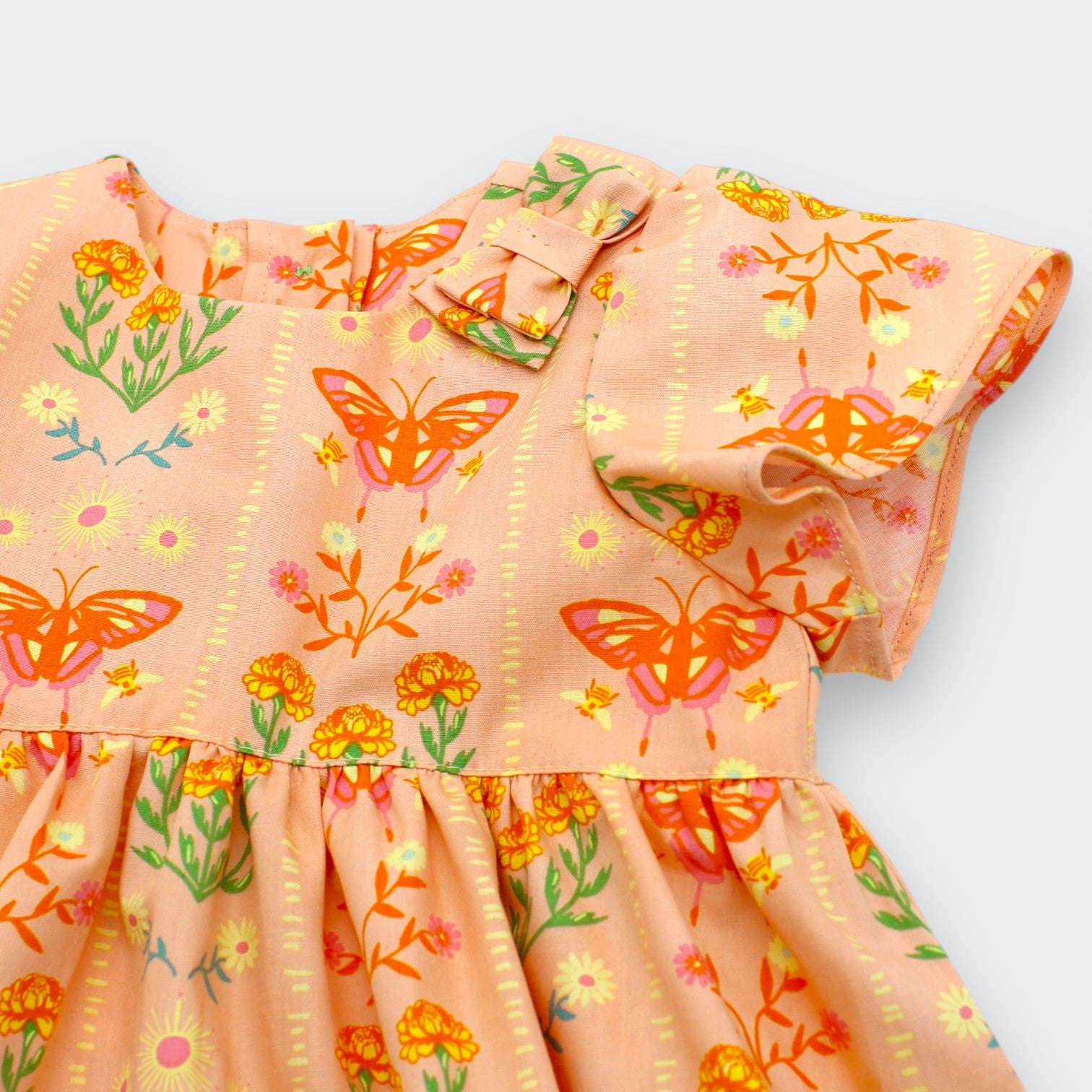 Close-up of orange butterfly and marigold print on Little Moony Butterfly Meadow 