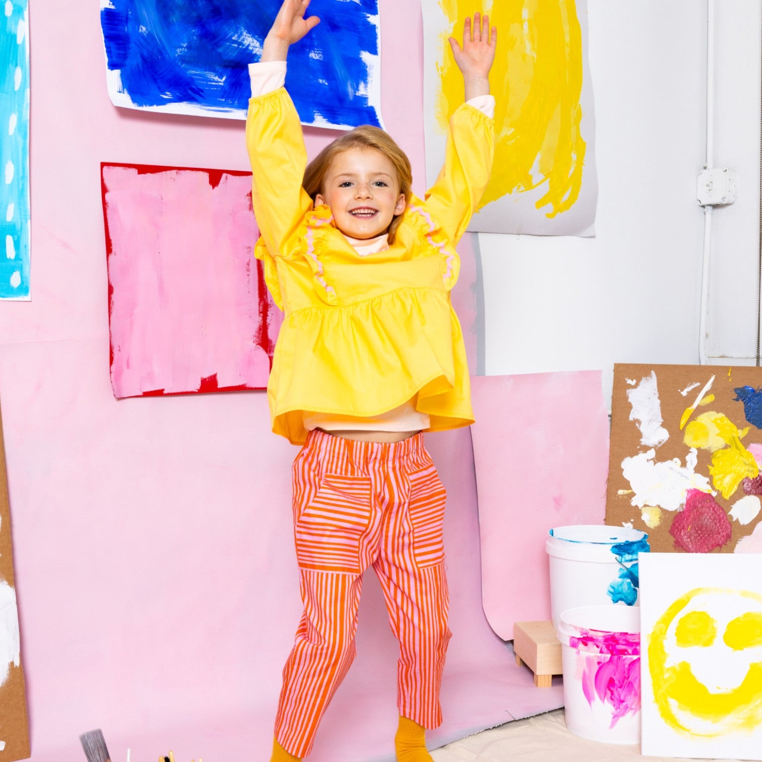 Girl wearing Little Moony cherry red and pink stripe patch pocket pants with yellow top