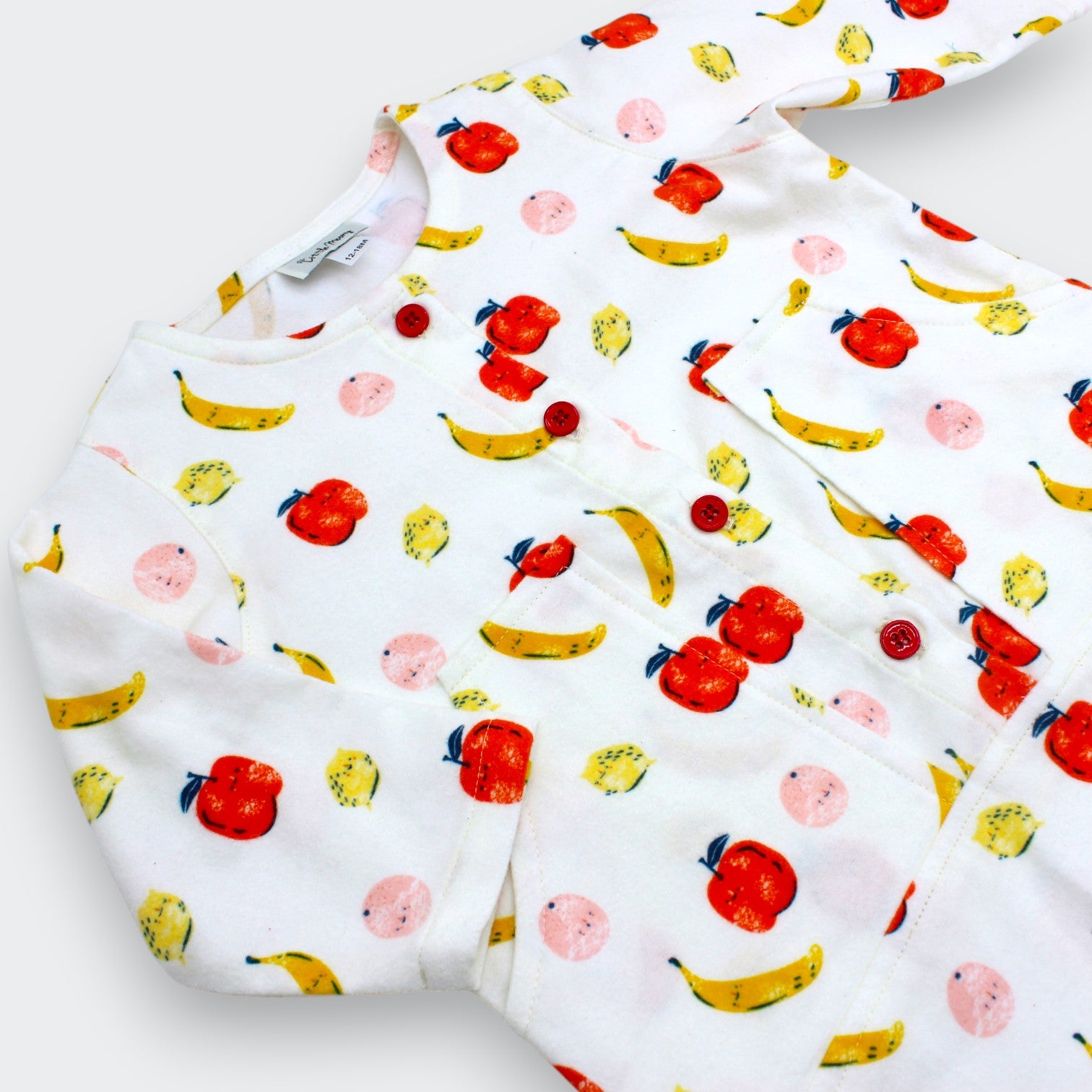 Close-up of apple banana and peach print with patch pocket detail on Little Moony