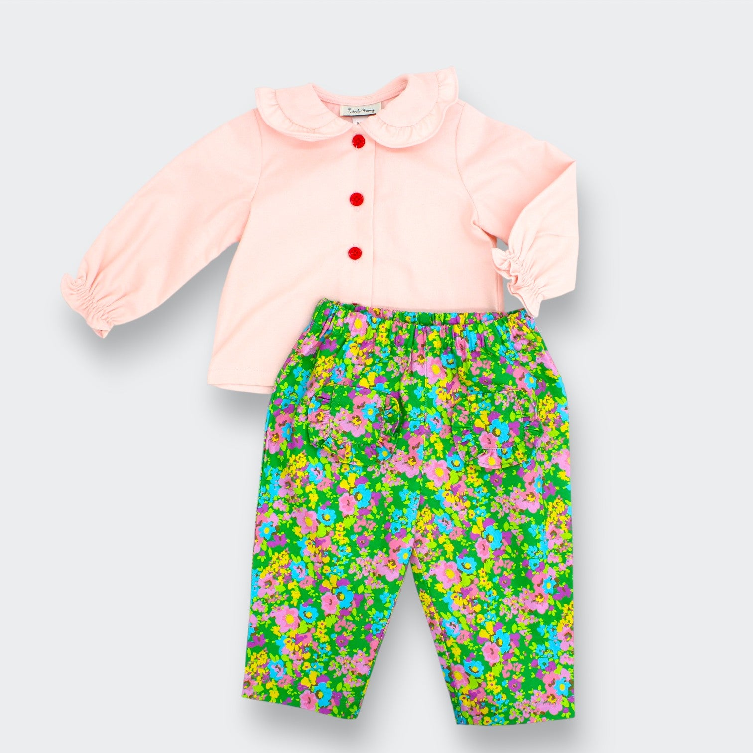 Children's outfit with pink top and floral pants on a light gray background