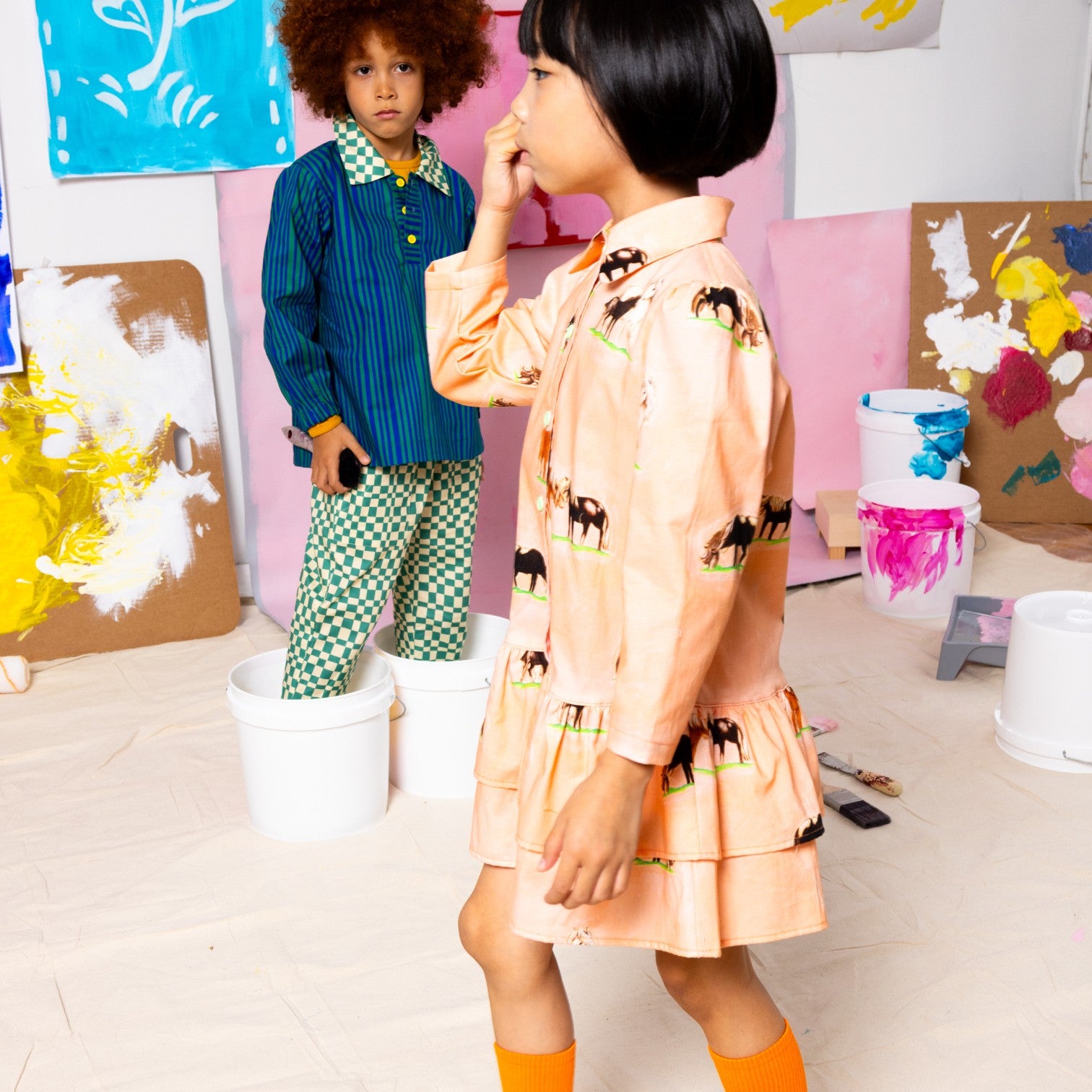 Girl  in Little Moony horse print tiered shirt dress, tailored bodice with two gathered tiers, peach ground