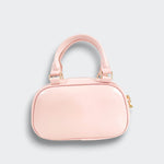 Back view of a pale pink bowler purse with twin handles, rounded edges, and gold-tone hardware on a light gray background.