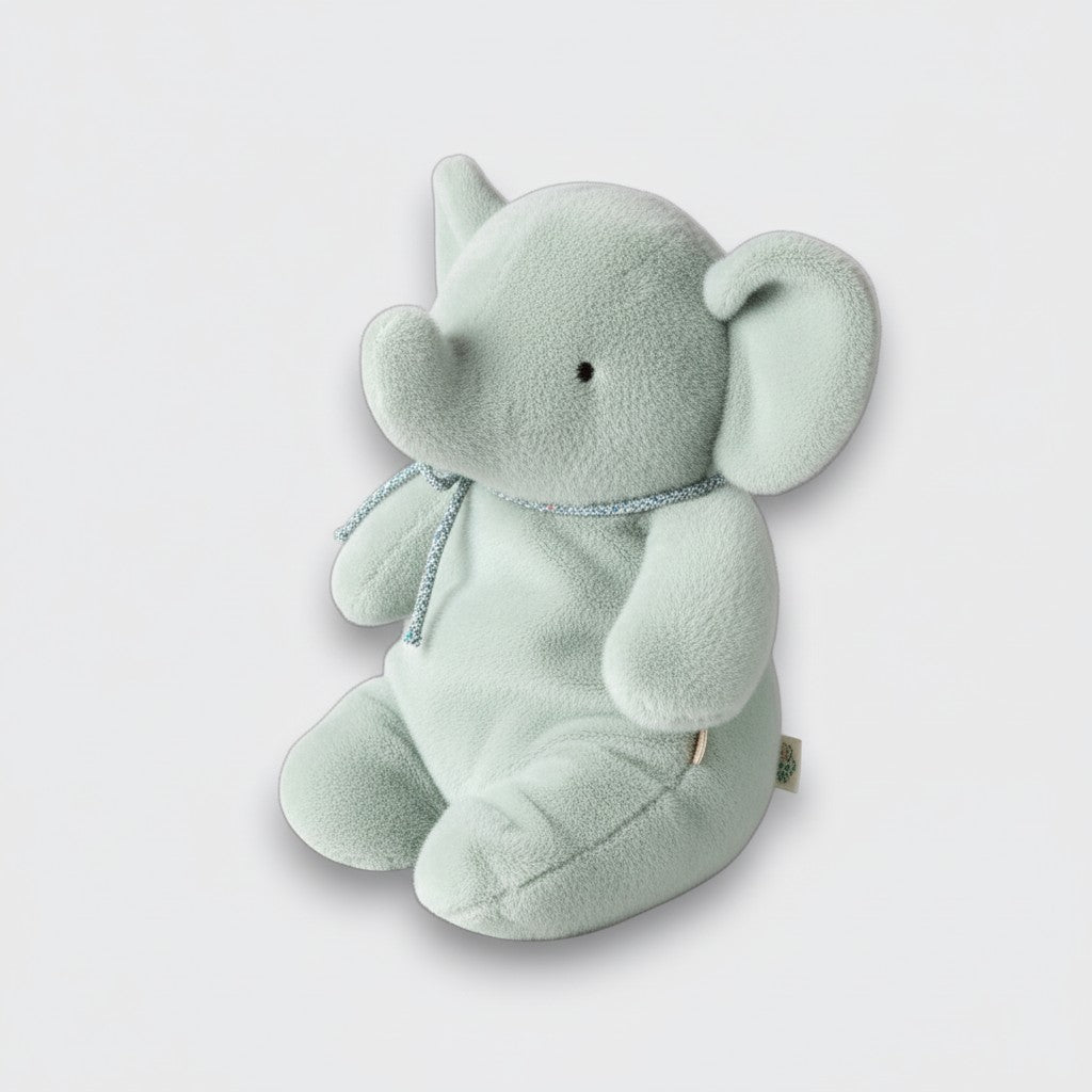 Side view of a soft mint elephant plush toy with a curled trunk, large ears, and a silver neck ribbon on a light gray background.