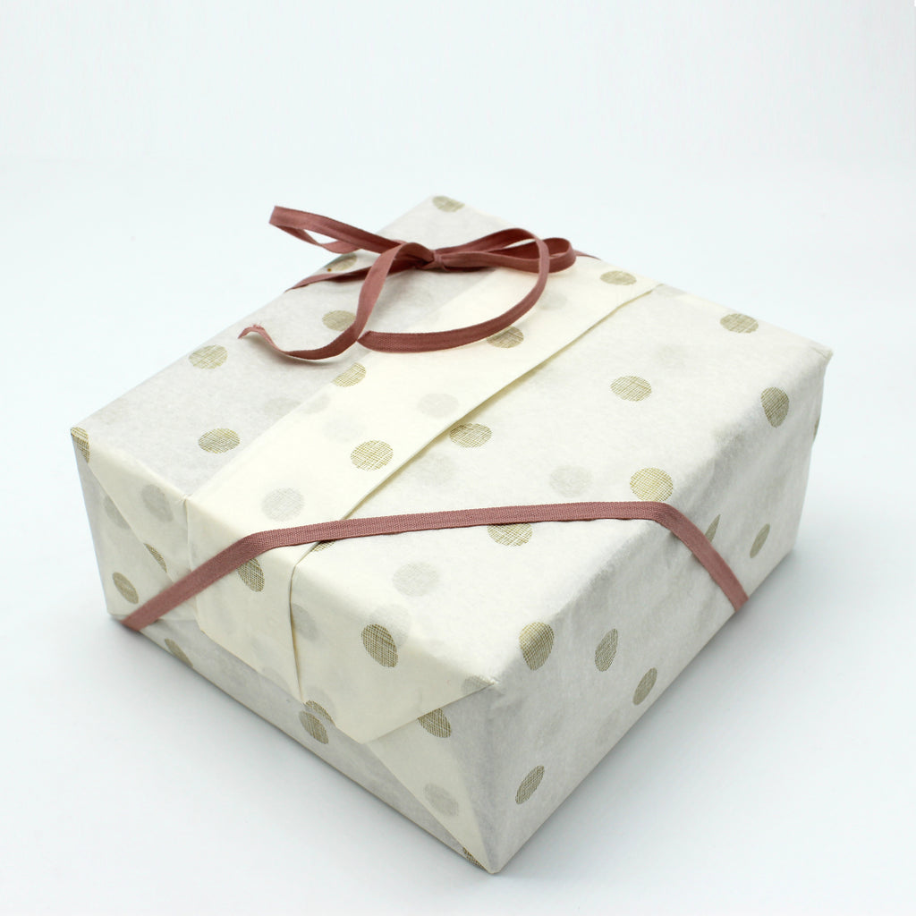 Sample picture of a wrapped box in polka dot tissue paper and dark pink ribbon bow tied.